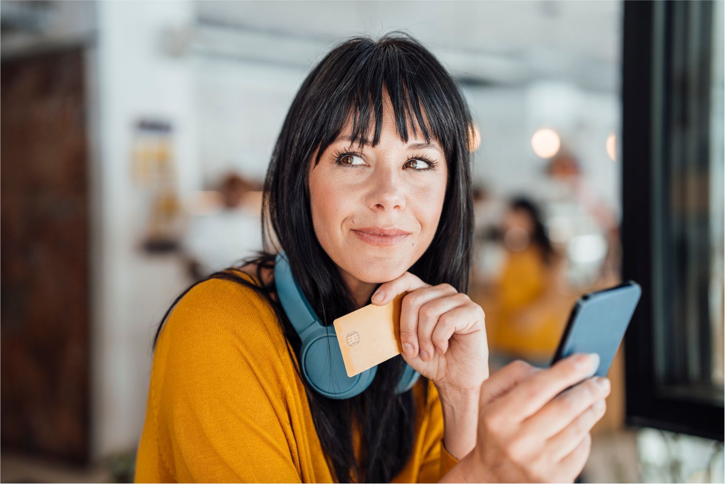 woman with headphones holding credit card